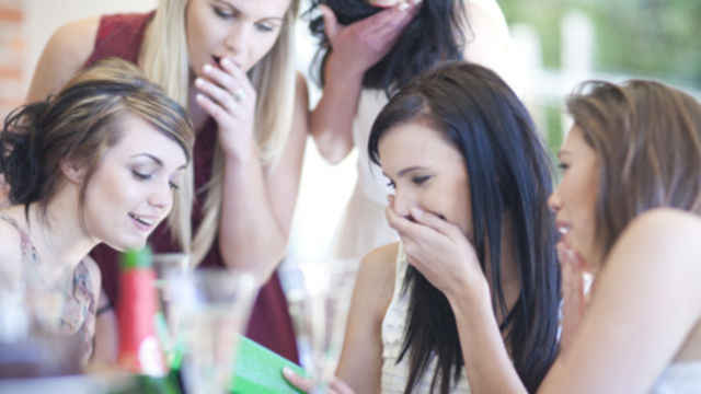 ryhmä yllättyneitä nuoria naisia ​​katsomassa kirjaa